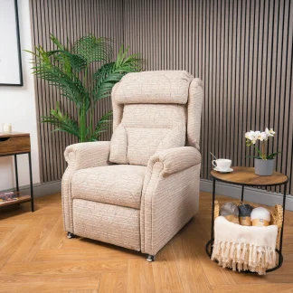 Recliners Surrey Riser Recliner with a lateral back cushion. Chair is in the upright position with a coffee table next to it and a green plant in the corner of the room behind.