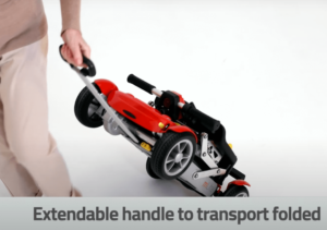 An electric mobility scooter that manually folds and has an extendable carry handle to pull it along on its wheels