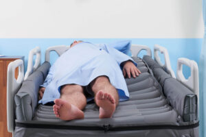 patient is lying on the Wellell Optima Turn Mattress whilst being protected from rolling into bed side rails thanks to the Side Bolsters