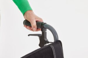 a hand is holding the push handle at the rear of the Motion Magnelite Manual Wheelchair but isn't applying the brake