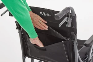 Attendant is opening up the compartment on the rear of the Motion Magnetite Transit Wheelchair