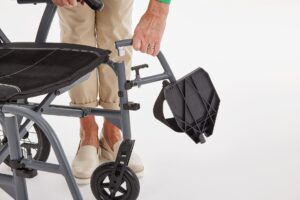 footrests are being removed by an attendant on the Motion Magnelite Transit Wheelchair
